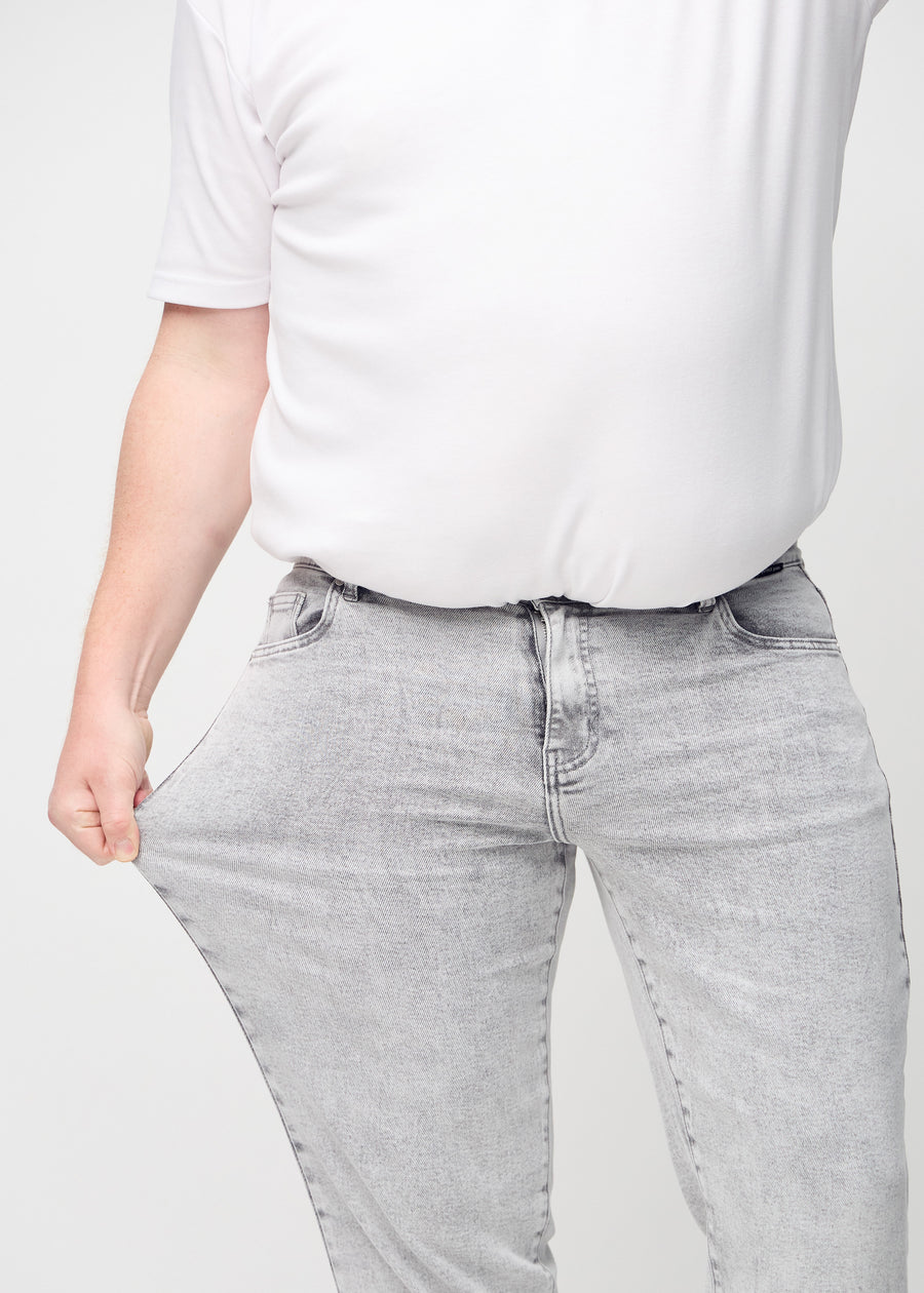 Plus-size-modellen strekker jeansene ved låret for å vise stretch.