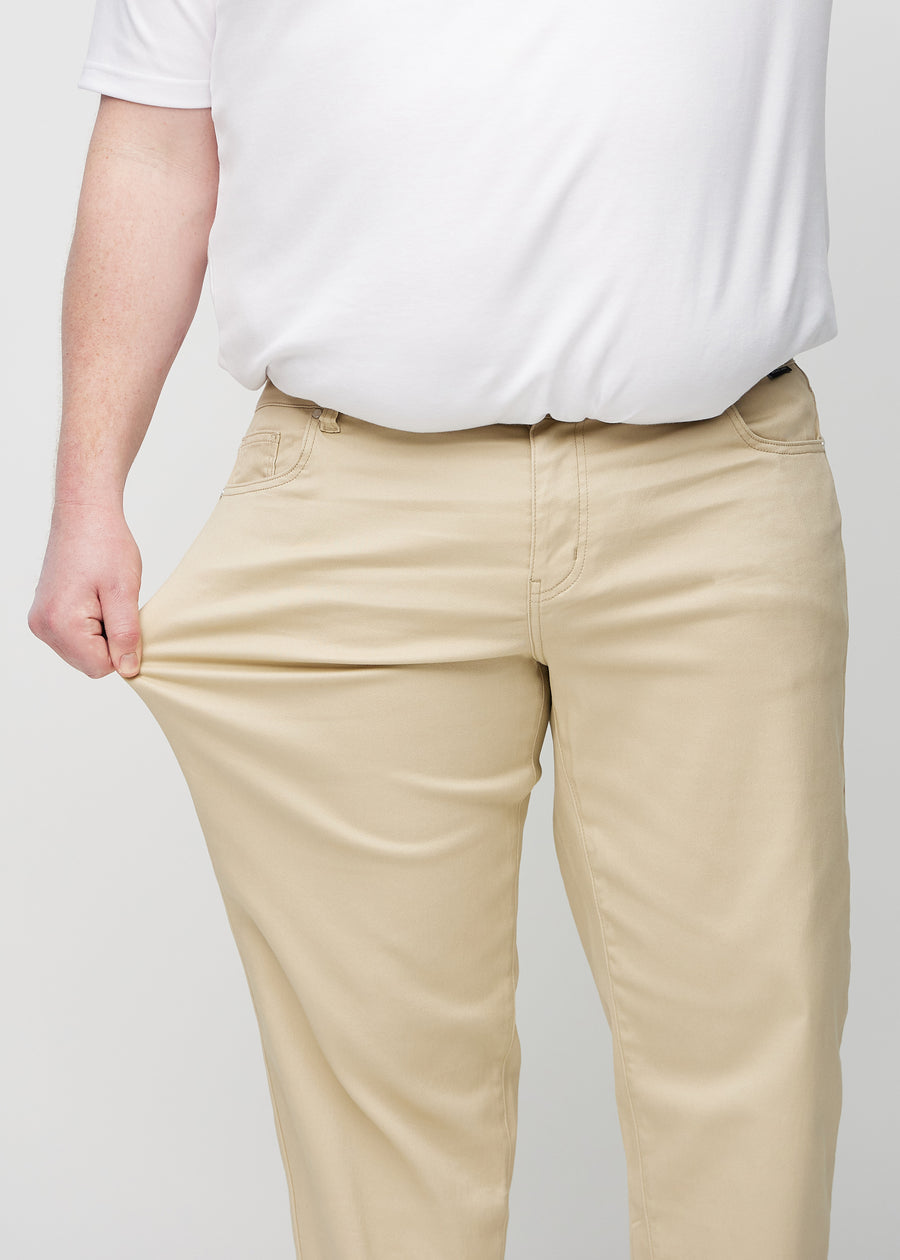 Plus-size-modellen strekker jeansene ved låret for å vise stretch.