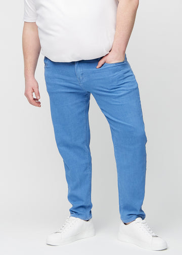 Blå regular jeans, modellnavn Geraniums, som går rett ned langs benet på en plus-size-modell, sett forfra.