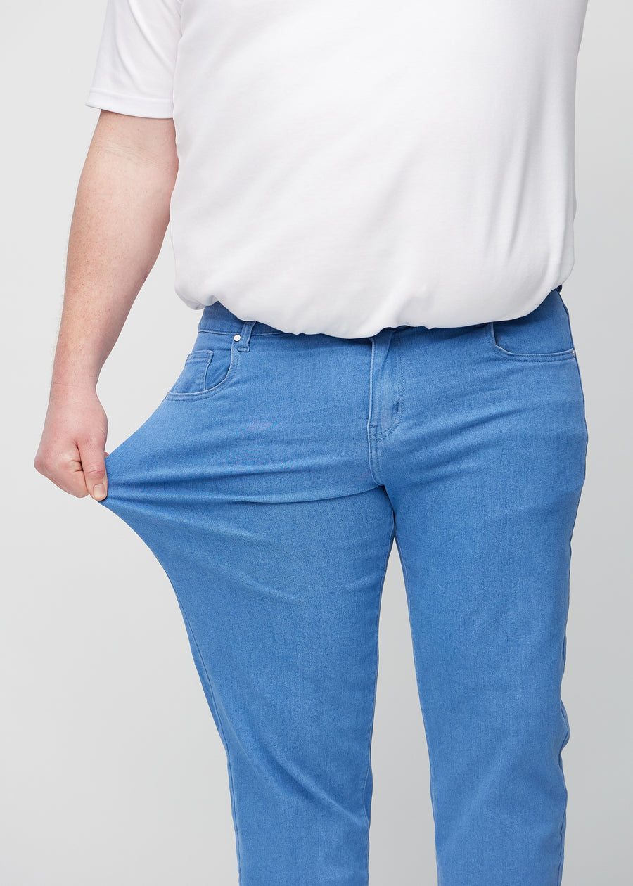 En plus-size-modell strekker jeansene ved låret for å vise stretch.