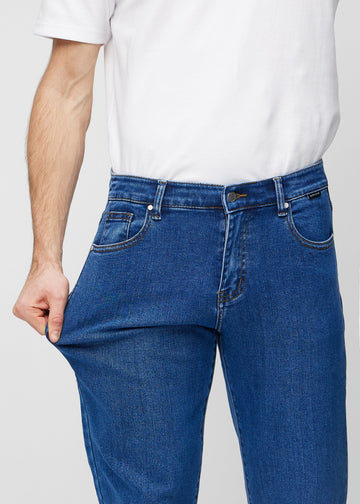 Modellen strekker jeansene ved låret for å vise stretch.