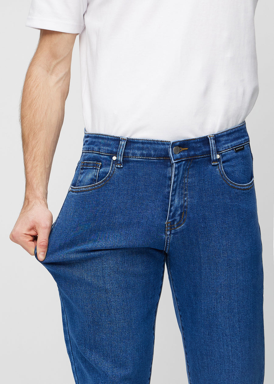 Modellen strekker jeansene ved låret for å vise stretch.