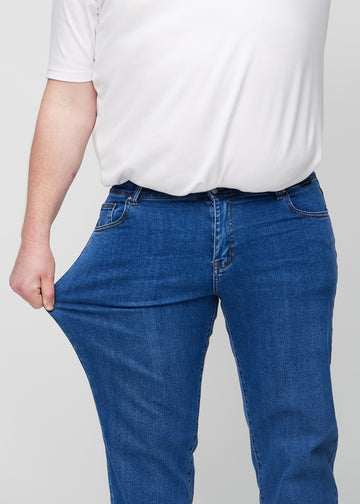 Plus-size-modellen strekker jeansene ved låret for å vise stretch.