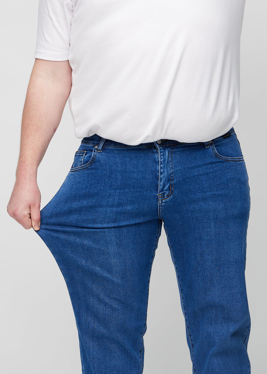 Plus-size-modellen strekker jeansene ved låret for å vise stretch.