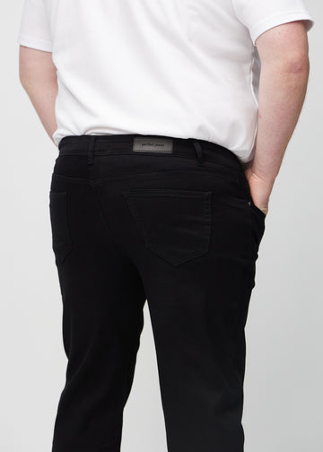 Svarte regular jeans sett bakfra på nært hold på en plus-size-modell for å vise detaljer.