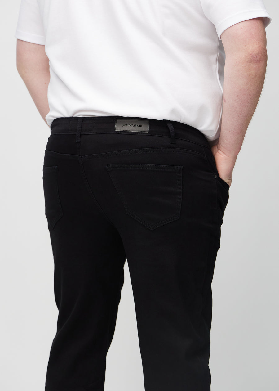 Svarte regular jeans sett bakfra på nært hold på en plus-size-modell for å vise detaljer.