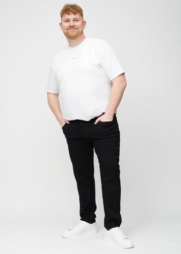 Fullt bilde av en plus-size-modell i svarte regular jeans.