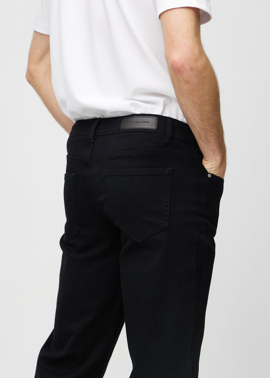 Svarte regular jeans sett bakfra på nært hold for å vise detaljer.