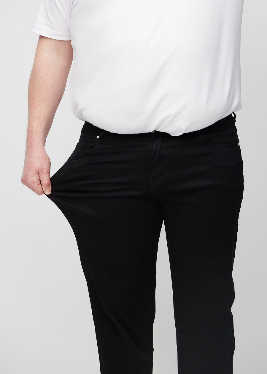 Plus-size-modellen strekker jeansene ved låret for å vise stretch.