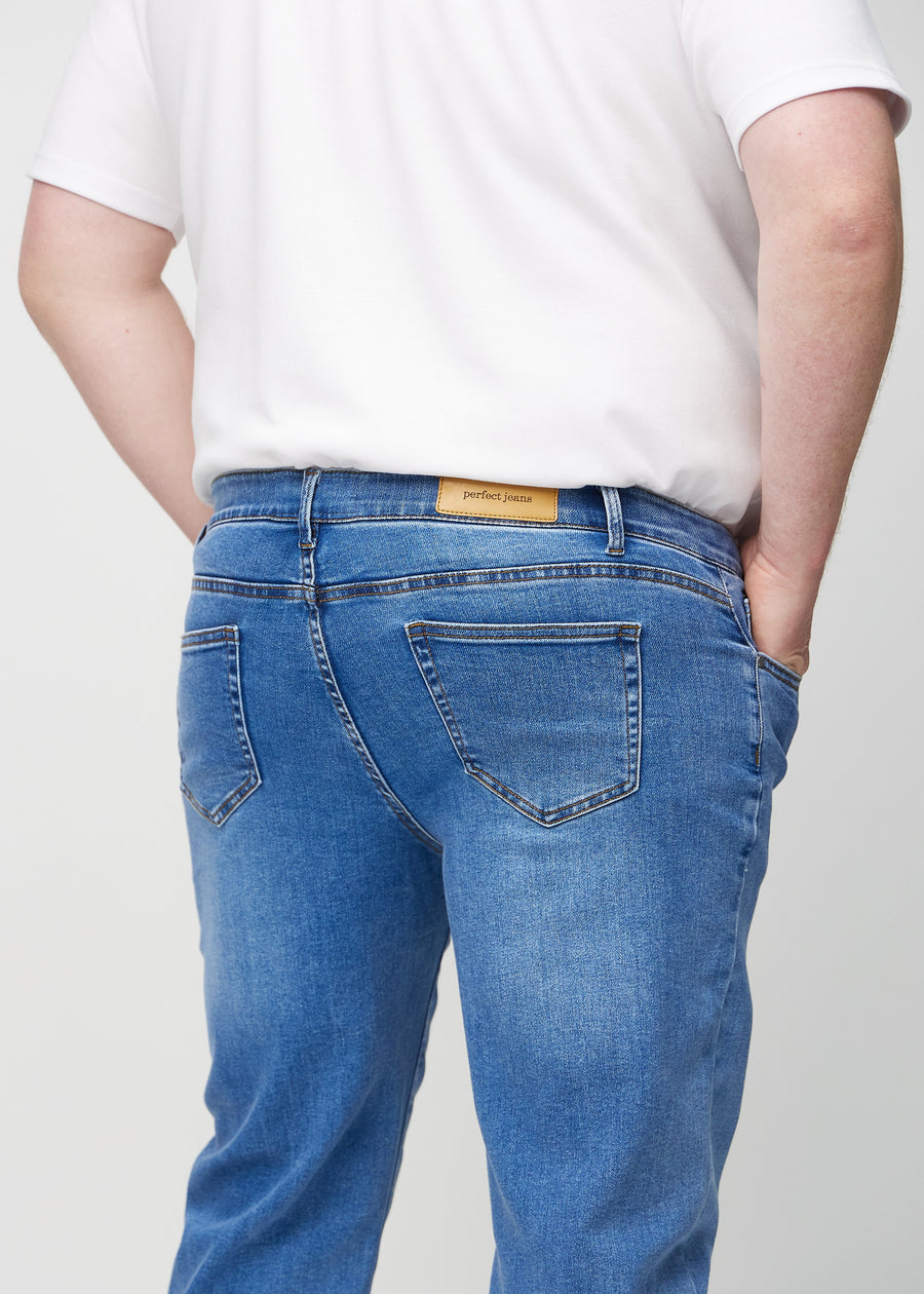 Denim regular jeans sett bakfra på nært hold på en plus-size-modell for å vise detaljer.