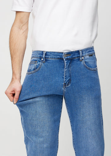 Modellen strekker jeansene ved låret for å vise stretch.