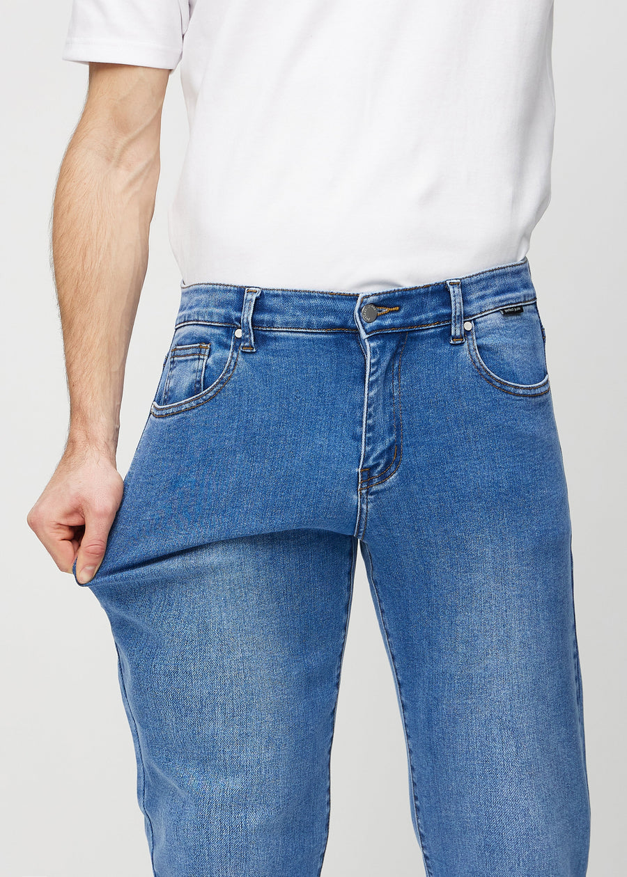 Modellen strekker jeansene ved låret for å vise stretch.