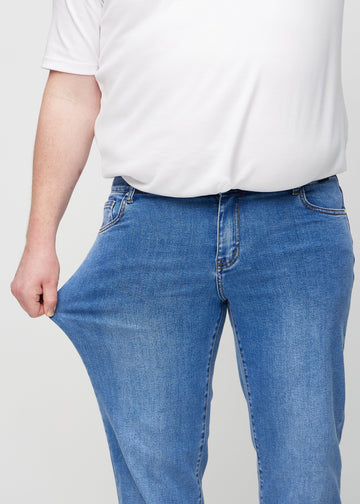 Plus-size-modellen strekker jeansene ved låret for å vise stretch.
