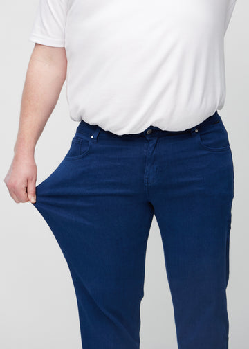 Plus-size-modellen strekker jeansene ved låret for å vise stretch.