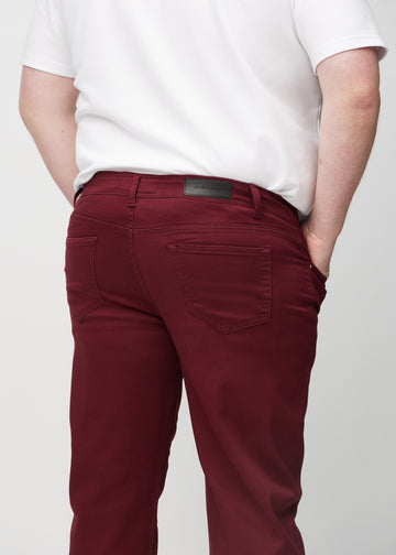 Mørkerøde regular jeans sett bakfra på nært hold på en plus-size-modell for å vise detaljer.