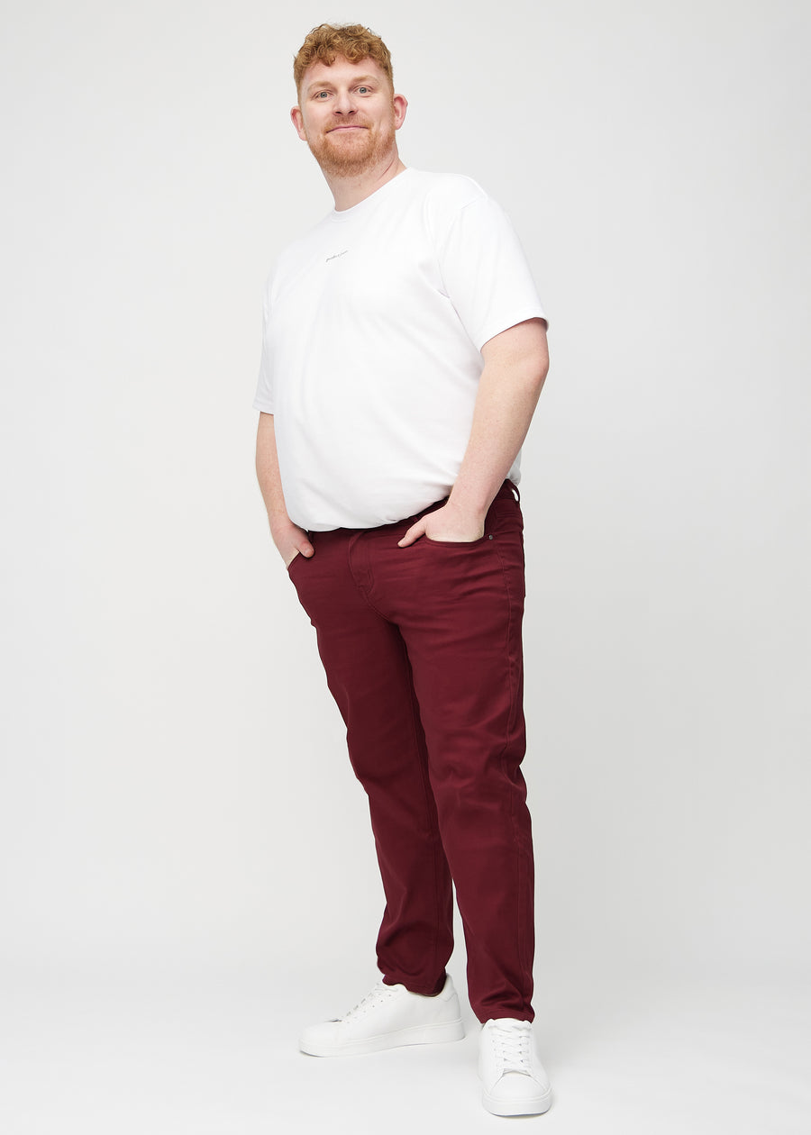 Fullt bilde av en plus-size-modell i mørkerøde regular jeans.