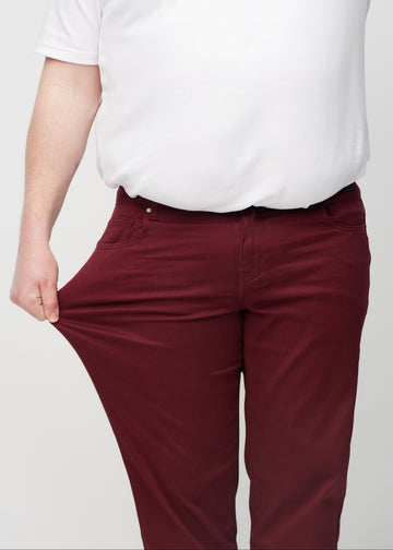 Plus-size-modellen strekker jeansene ved låret for å vise stretch.