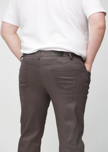 Gråbrune regular jeans sett bakfra på nært hold på en plus-size-modell for å vise detaljer.