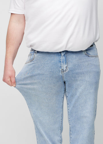 Plus-size-modellen strekker jeansene ved låret for å vise stretch.
