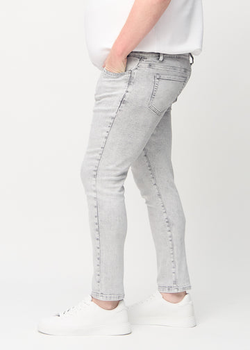 Lysegrå denimjeans i slim fit sett fra siden på en plus-size-modell.