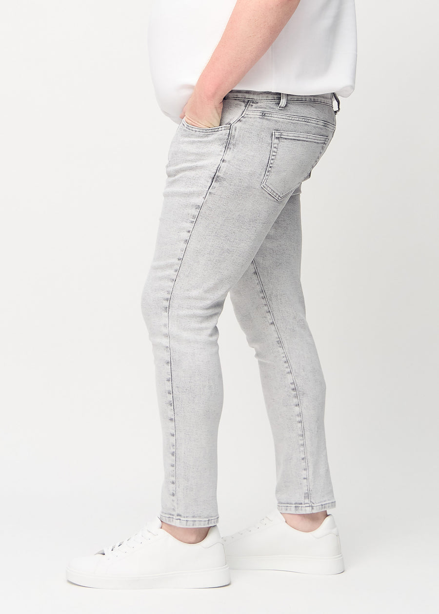 Lysegrå denimjeans i slim fit sett fra siden på en plus-size-modell.