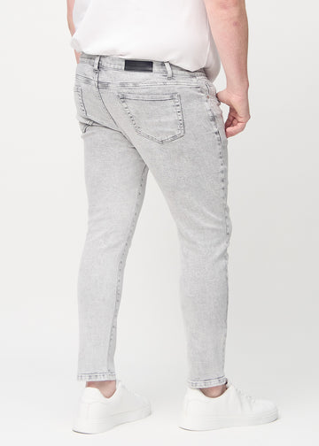 Lysegrå denimjeans i slim fit sett bakfra på en plus-size-modell for å vise hele produktet.
