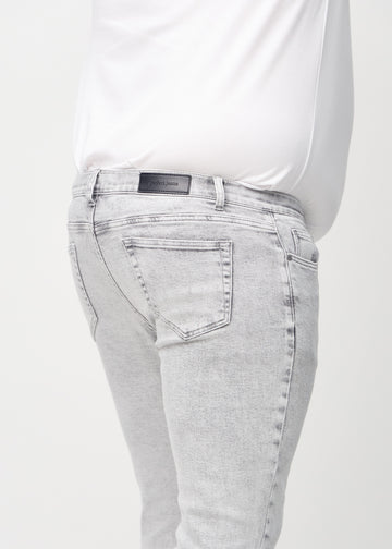 Nærbilde bakfra av lysegrå denimjeans i slim fit på en plus-size-modell som viser detaljer.
