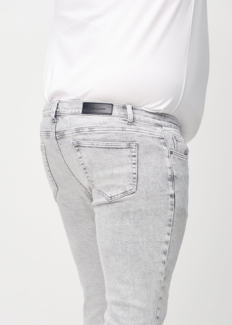 Nærbilde bakfra av lysegrå denimjeans i slim fit på en plus-size-modell som viser detaljer.