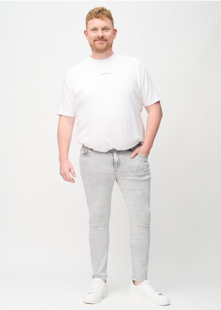 Helbilde av en plus-size-modell i lysegrå denimjeans i slim fit.