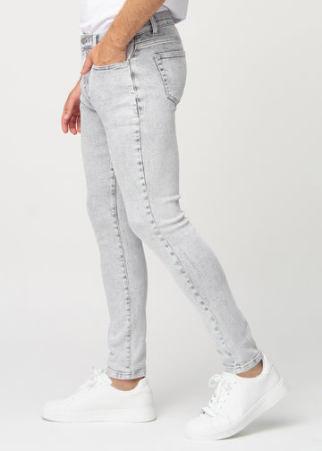 Lysegrå denimjeans i slim fit sett fra siden på en modell.