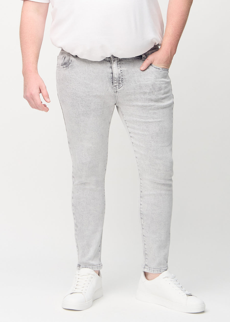 Lysegrå denimjeans i slim fit, modellnavn Ashes, som sitter tett langs bena på en plus-size-modell, sett forfra.