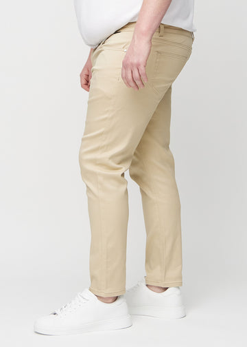 Beige jeans i slim fit sett fra siden på en plus-size-modell.