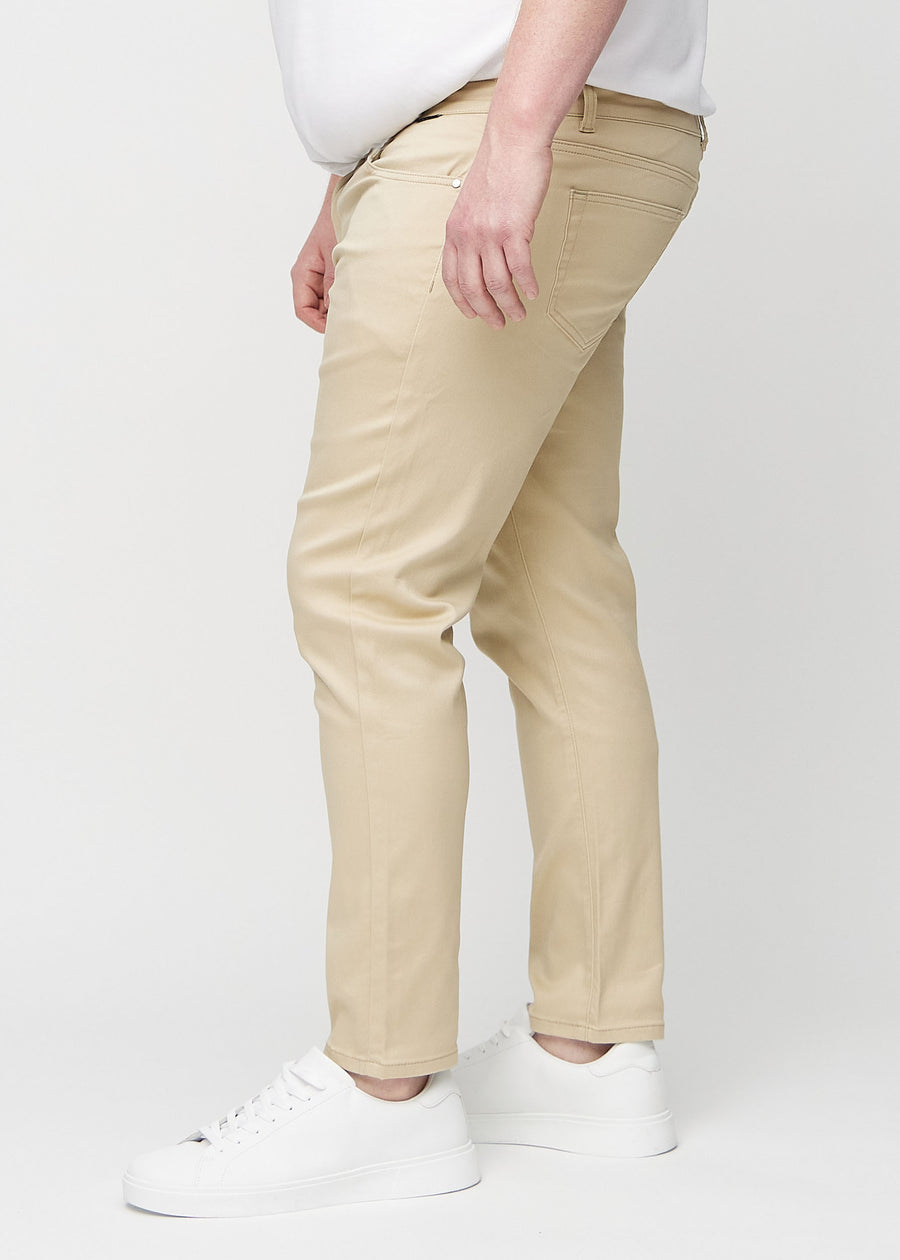 Beige jeans i slim fit sett fra siden på en plus-size-modell.