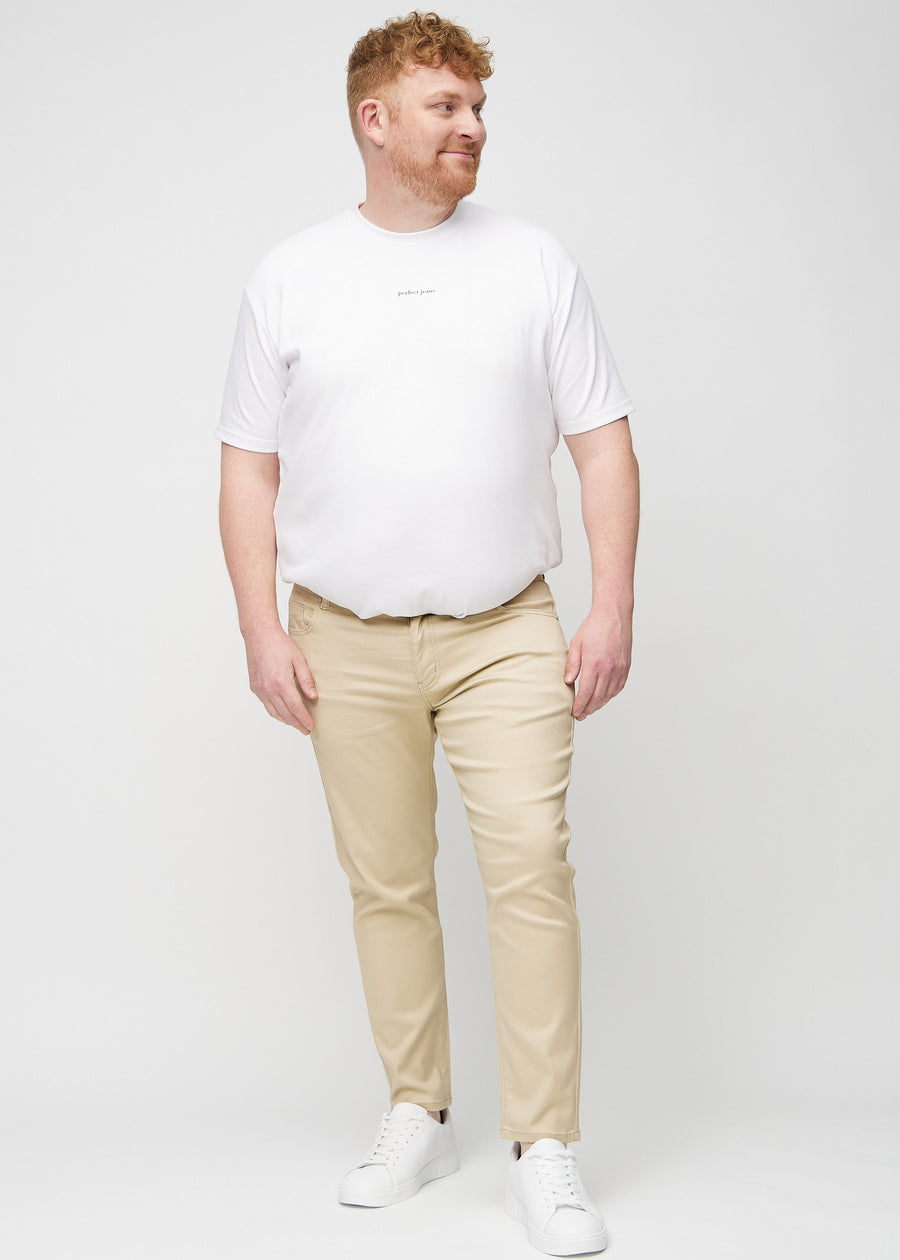 Helbilde av en plus-size-modell i beige jeans i slim fit.