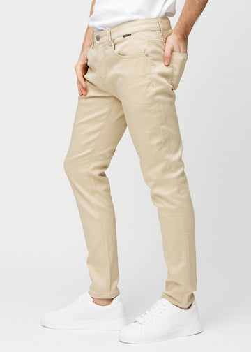 Beige jeans i slim fit sett fra siden på en modell.