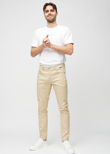 Helbilde av en modell i beige jeans i slim fit.