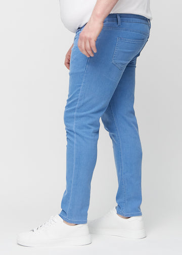 Blå jeans i slim fit sett fra siden på en plus-size-modell.