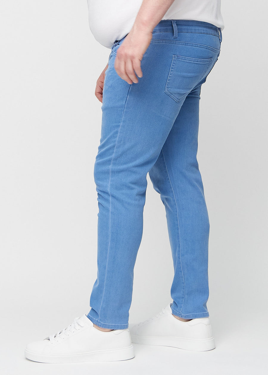 Blå jeans i slim fit sett fra siden på en plus-size-modell.