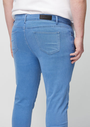 Nærbilde bakfra av blå jeans i slim fit på en plus-size-modell som viser detaljer.