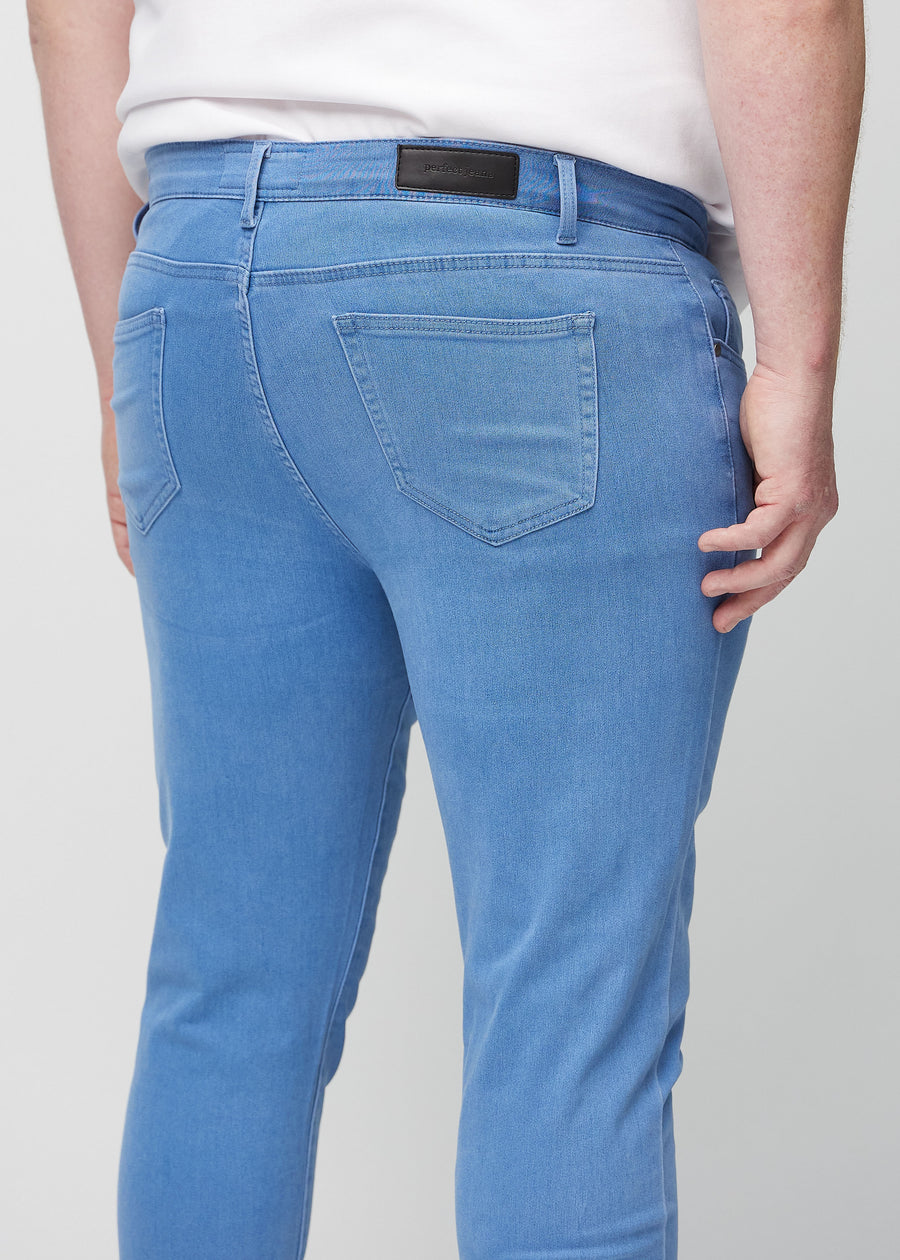 Nærbilde bakfra av blå jeans i slim fit på en plus-size-modell som viser detaljer.