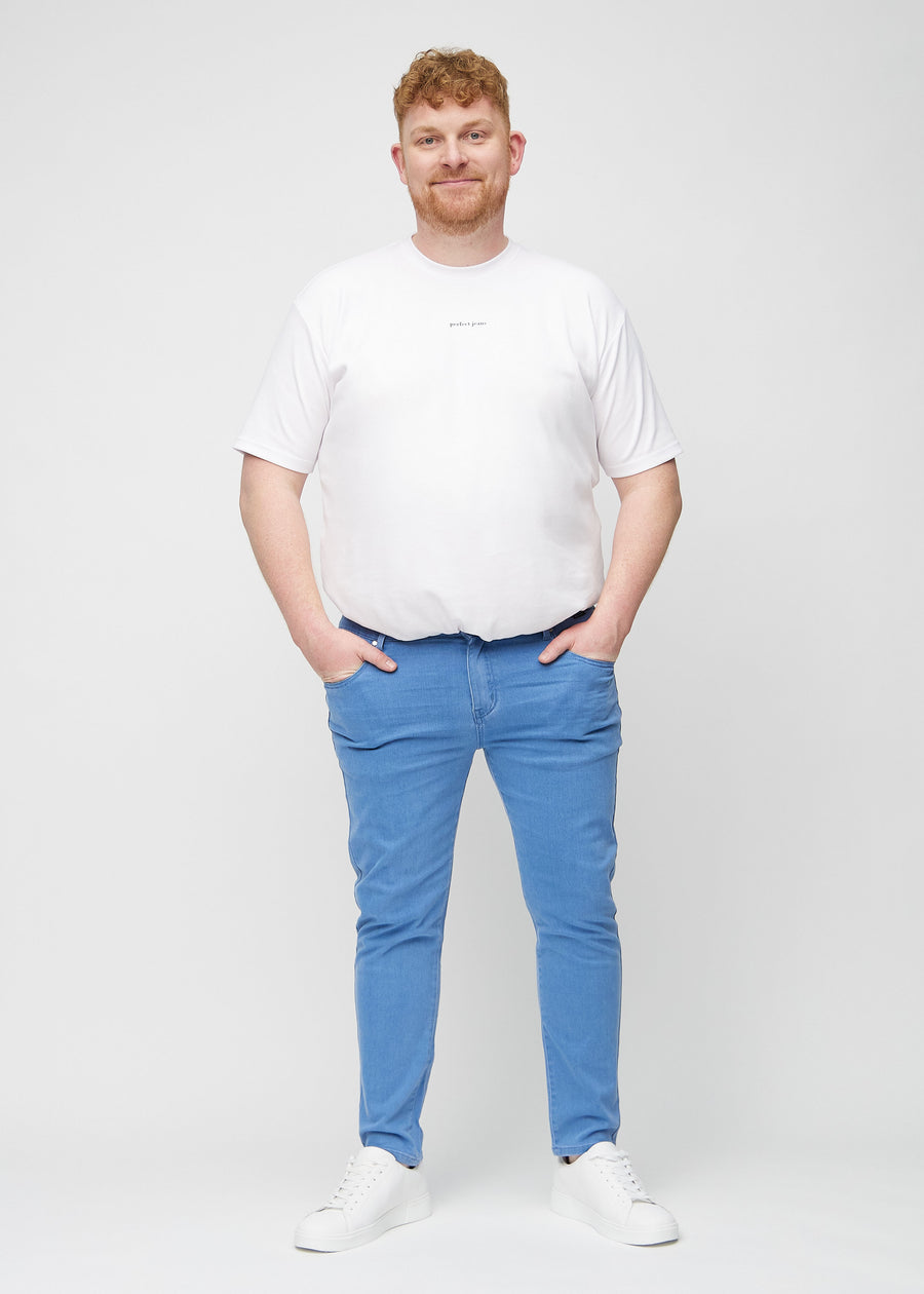 Helbilde av en plus-size-modell i blå jeans i slim fit.