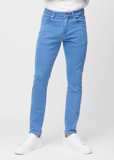 Blå jeans i slim fit, modellnavn Geraniums, som sitter tett langs bena, sett forfra.