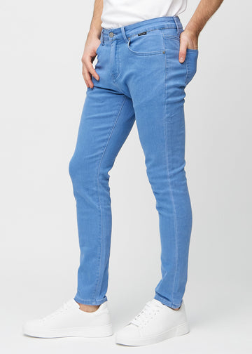 Blå jeans i slim fit sett fra siden på en modell.