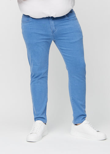 Blå jeans i slim fit, modellnavn Geraniums, som sitter tett langs bena på en plus-size-modell, sett forfra.