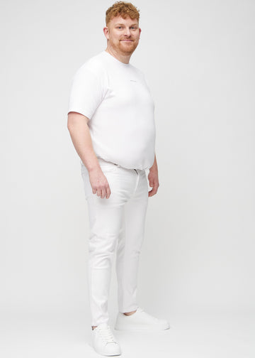 Helbilde av en plus-size-modell i hvite jeans i slim fit.
