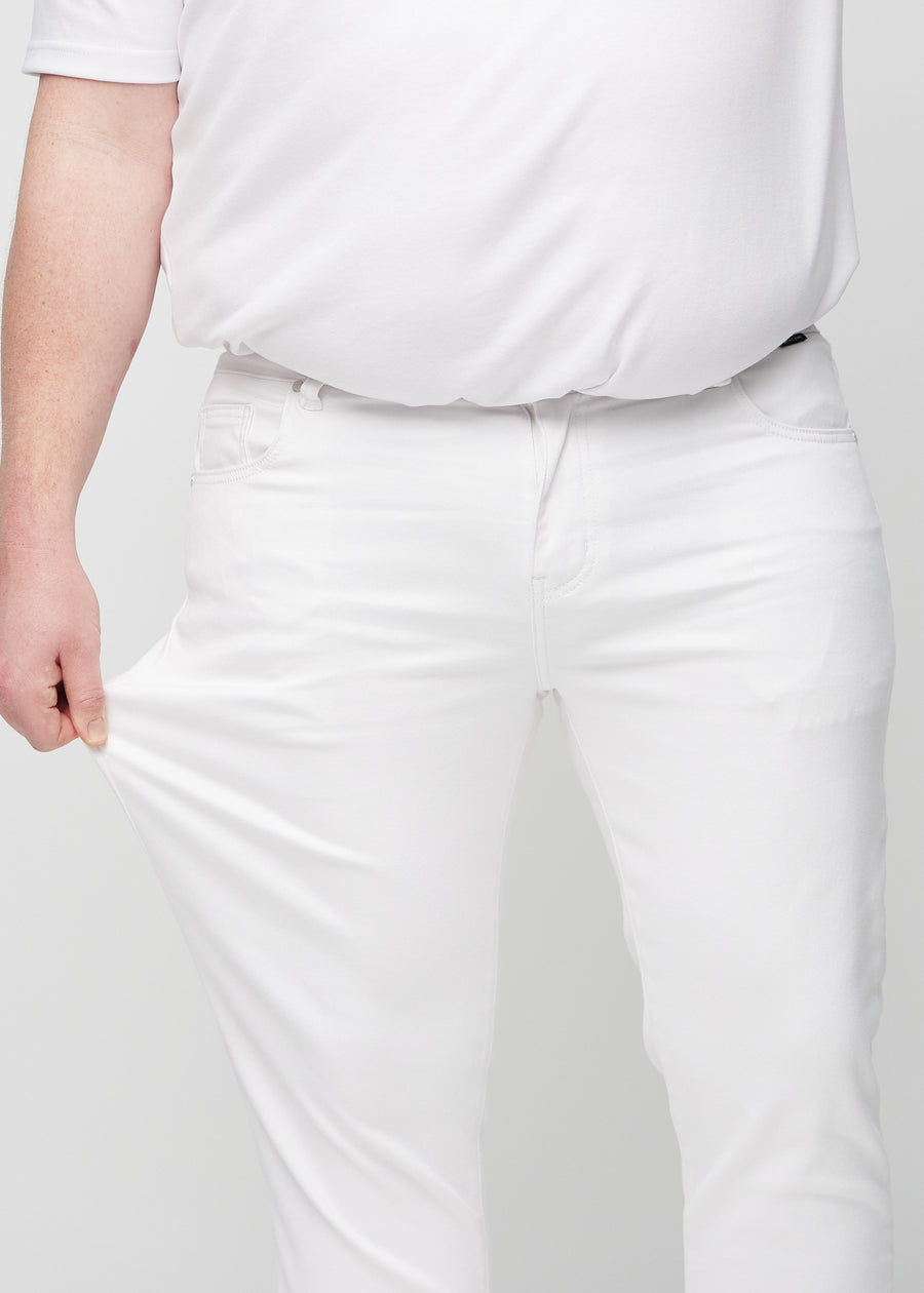 Plus-size-modell strekker jeansene ved låret for å vise materialets stretch.