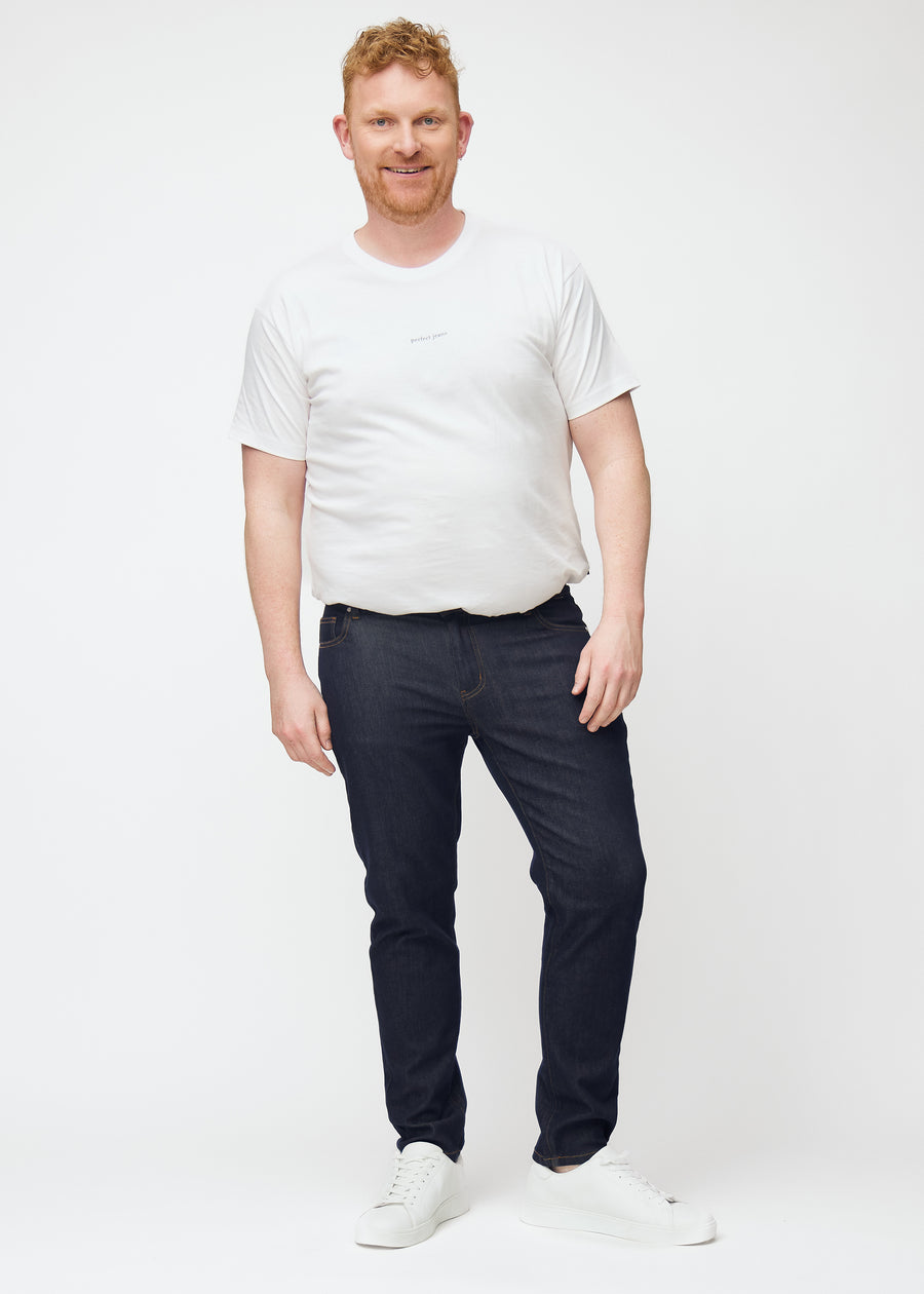 Fullt bilde av plus-size-modell i dyp mørkeblå denim jeans til menn i fargen Midnights med slim passform.