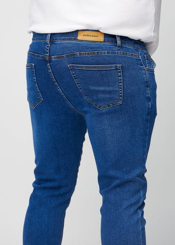 Nærbilde bakfra av mørkeblå denimjeans i slim fit på en plus-size-modell som viser detaljer.