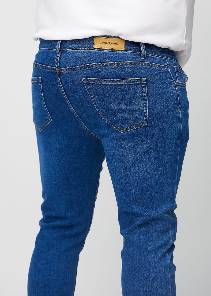 Nærbilde bakfra av mørkeblå denimjeans i slim fit på en plus-size-modell som viser detaljer.