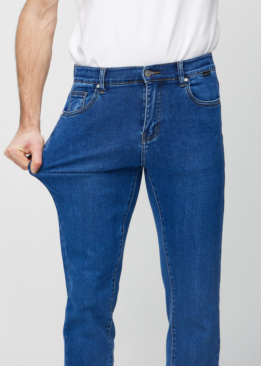 Modell strekker jeansene ved låret for å vise materialets stretch.